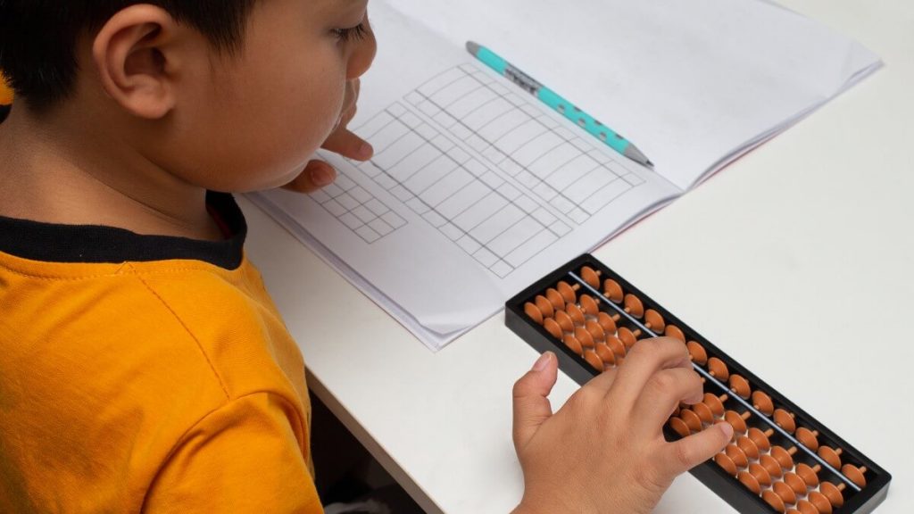 Asian father sitting next to daughter learning on tablet