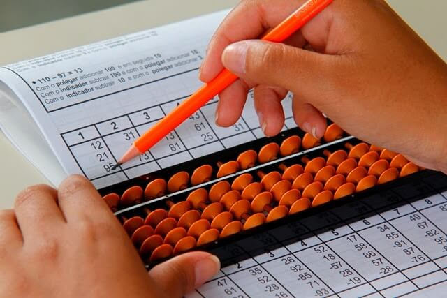 Child learning to represent tens and hundreds on soroban